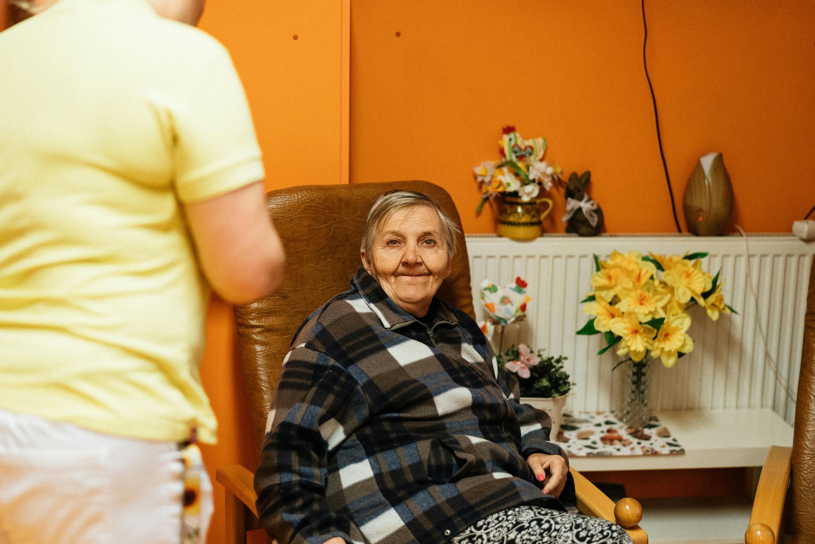 A caregiver helping an older adult walk down a hallway in an assisted living community