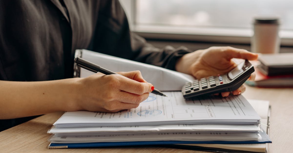 A freelancer reviewing health insurance for self employed paperwork and a calculator at a desk